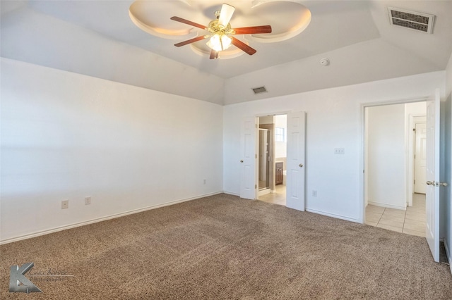 unfurnished bedroom with ensuite bathroom, lofted ceiling, light colored carpet, ceiling fan, and a tray ceiling