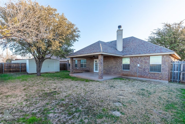 rear view of property with a storage unit, a yard, and a patio area