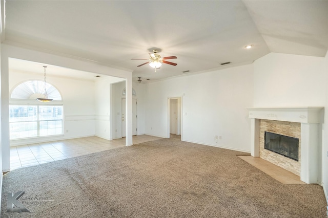 unfurnished living room with lofted ceiling, light carpet, ornamental molding, a tile fireplace, and ceiling fan