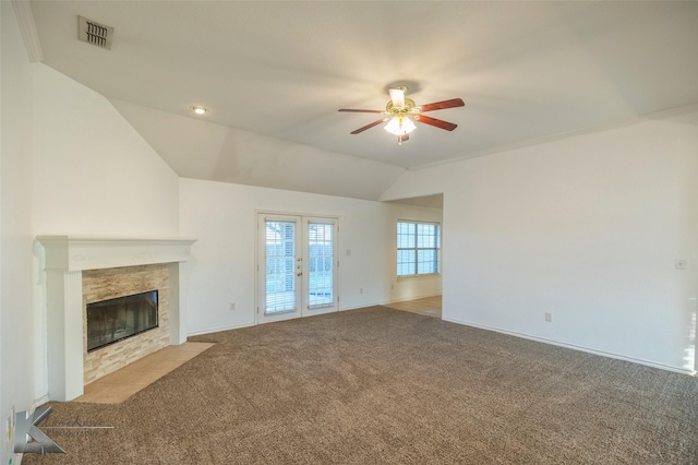 unfurnished living room featuring french doors, vaulted ceiling, light carpet, ceiling fan, and a tiled fireplace