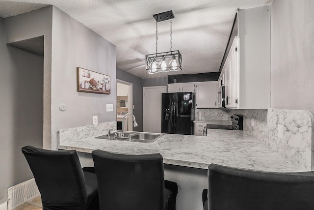 kitchen with sink, tasteful backsplash, black appliances, pendant lighting, and white cabinets