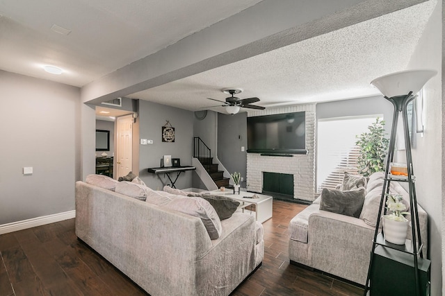 living room with ceiling fan, a textured ceiling, dark hardwood / wood-style flooring, and a fireplace