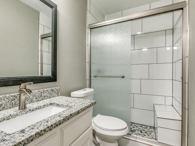 bathroom featuring vanity, a shower with shower door, and toilet