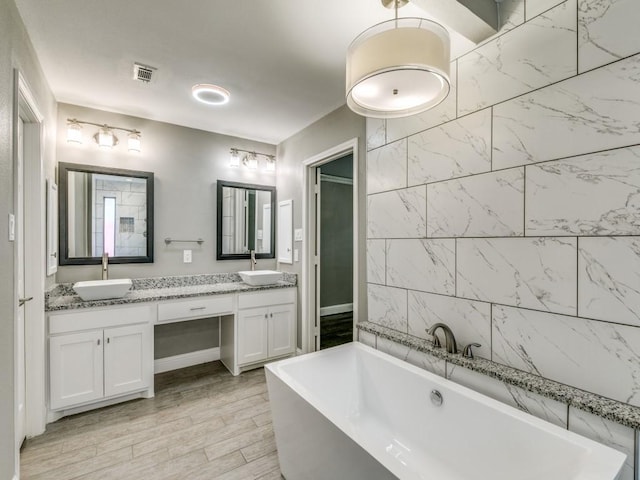 bathroom with hardwood / wood-style flooring, vanity, and a bathing tub