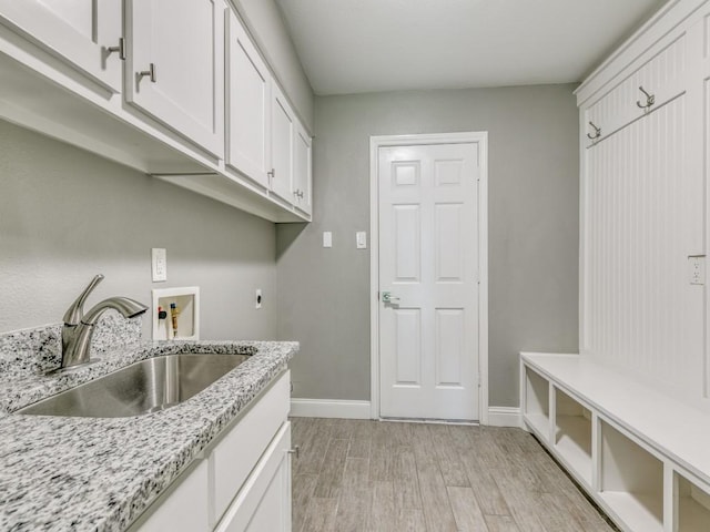 washroom featuring sink, cabinets, light hardwood / wood-style flooring, hookup for a washing machine, and hookup for an electric dryer