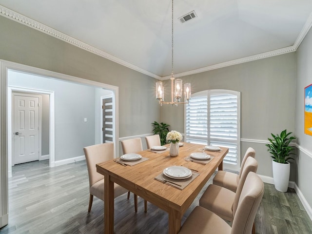 dining area featuring ornamental molding, hardwood / wood-style floors, and a chandelier