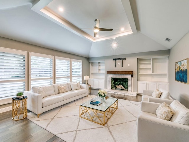 living room featuring lofted ceiling, hardwood / wood-style floors, a fireplace, and ceiling fan