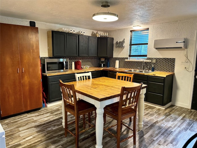 kitchen featuring sink, backsplash, a wall mounted AC, and light wood-type flooring