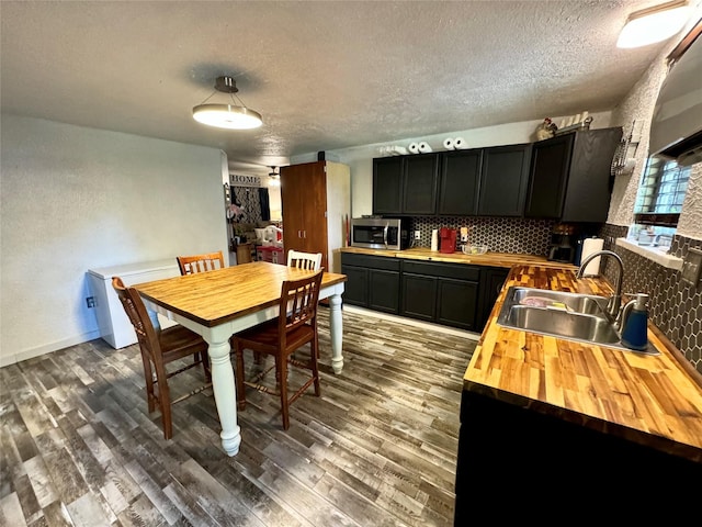 dining area featuring wood-type flooring, sink, and a textured ceiling