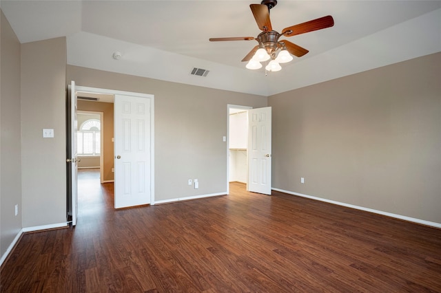 unfurnished bedroom with dark hardwood / wood-style flooring, a walk in closet, lofted ceiling, and ceiling fan