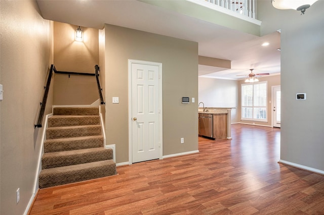 stairway featuring ceiling fan, sink, hardwood / wood-style floors, and a towering ceiling