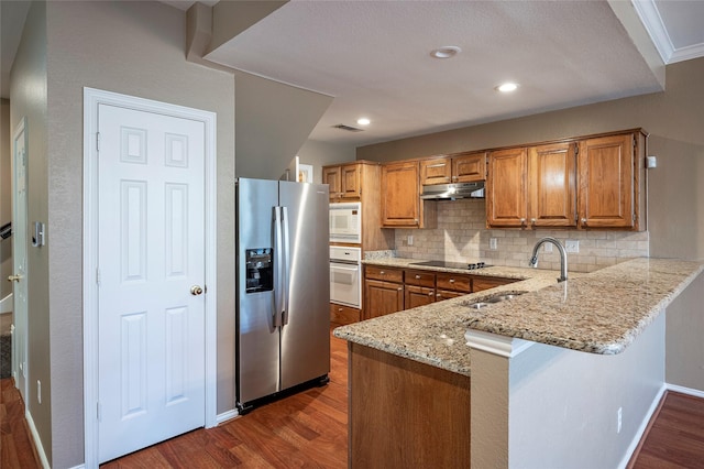 kitchen with light stone countertops, dark wood-type flooring, white appliances, and decorative backsplash