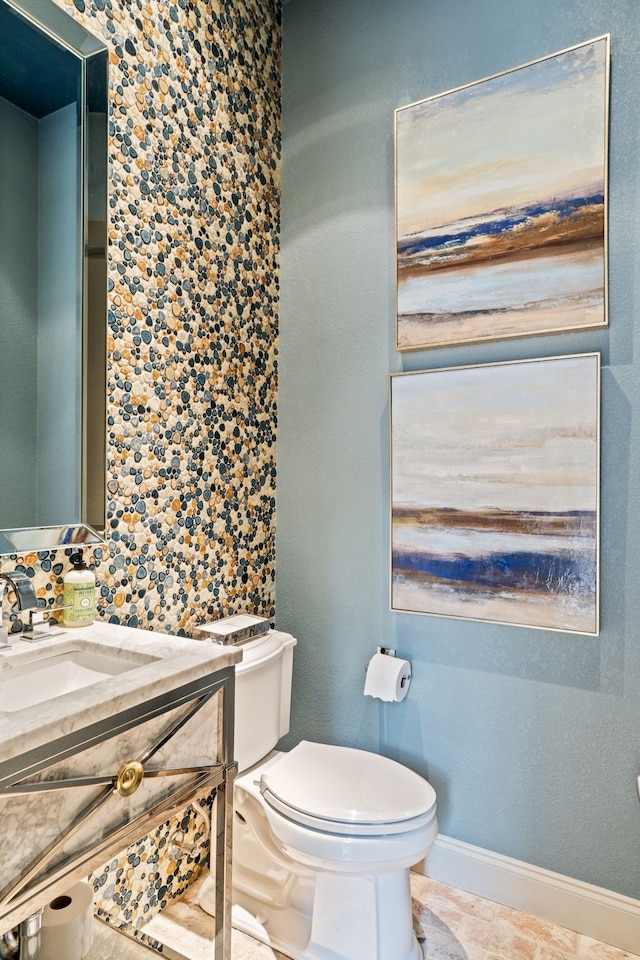 bathroom with toilet, vanity, and baseboards