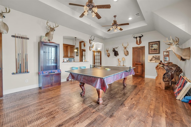 rec room featuring a raised ceiling, a ceiling fan, arched walkways, recessed lighting, and baseboards