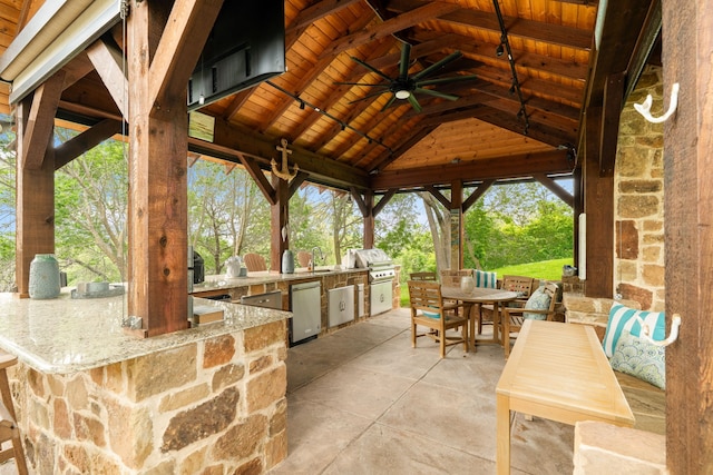 view of patio with area for grilling, a gazebo, a ceiling fan, outdoor dining space, and a grill