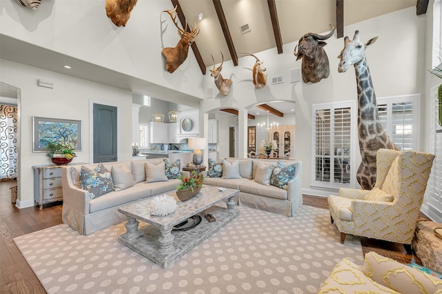 living room featuring visible vents, arched walkways, beamed ceiling, wood finished floors, and high vaulted ceiling