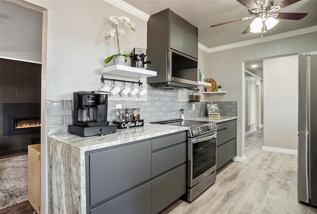 kitchen featuring gray cabinets, appliances with stainless steel finishes, tasteful backsplash, ornamental molding, and light wood-type flooring