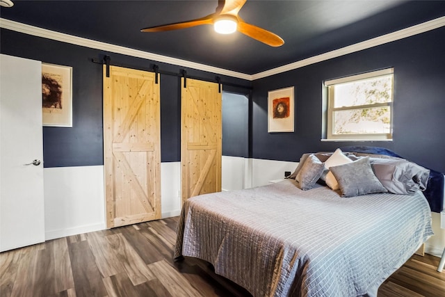 bedroom featuring hardwood / wood-style flooring, crown molding, a barn door, and ceiling fan