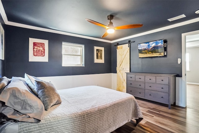 bedroom featuring hardwood / wood-style flooring, ornamental molding, a barn door, and ceiling fan