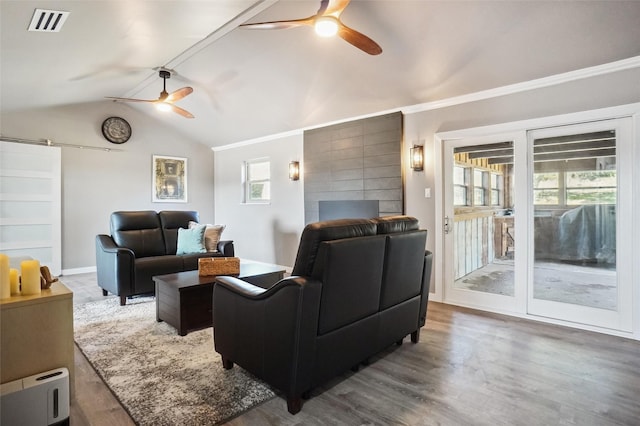 living room with crown molding, vaulted ceiling, hardwood / wood-style flooring, ceiling fan, and a barn door