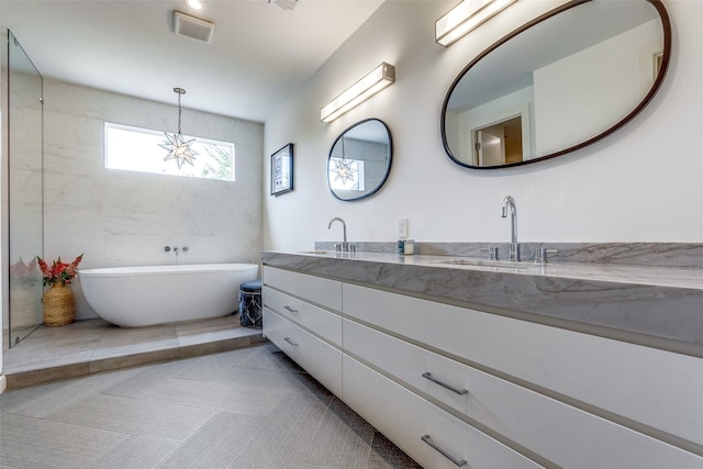 bathroom with tile patterned flooring, vanity, and a tub