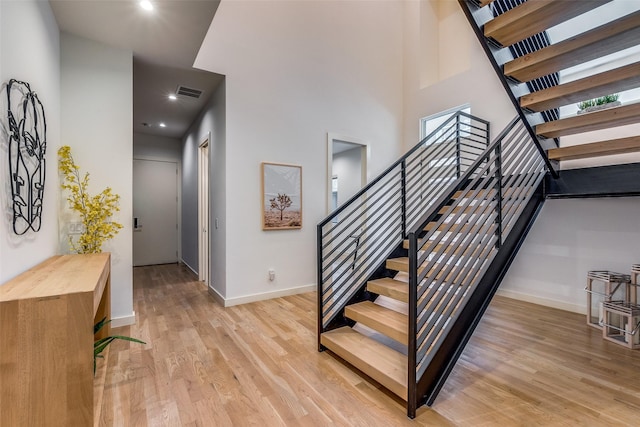 stairway featuring a towering ceiling and wood-type flooring