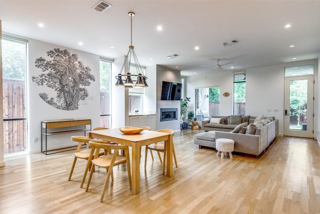 dining space with a large fireplace, a wealth of natural light, and light wood-type flooring