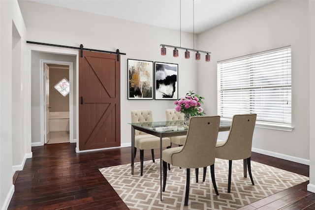 dining space featuring dark wood-style flooring, a barn door, and baseboards