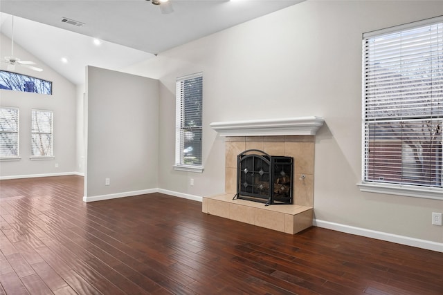 unfurnished living room with a tile fireplace, dark hardwood / wood-style flooring, vaulted ceiling, and ceiling fan