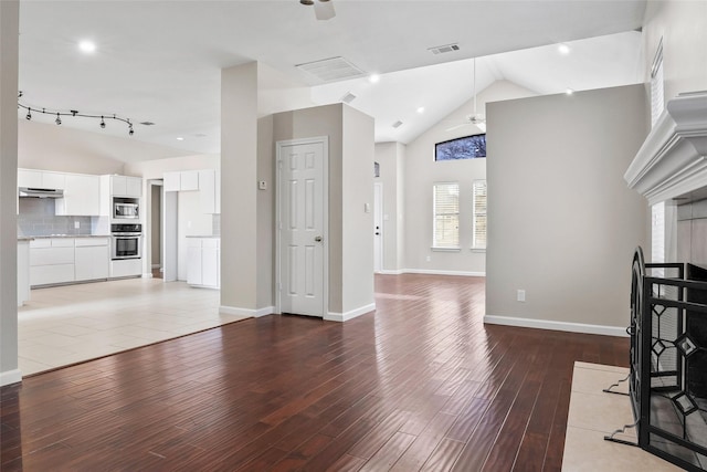 unfurnished living room featuring wood-type flooring, high vaulted ceiling, and ceiling fan