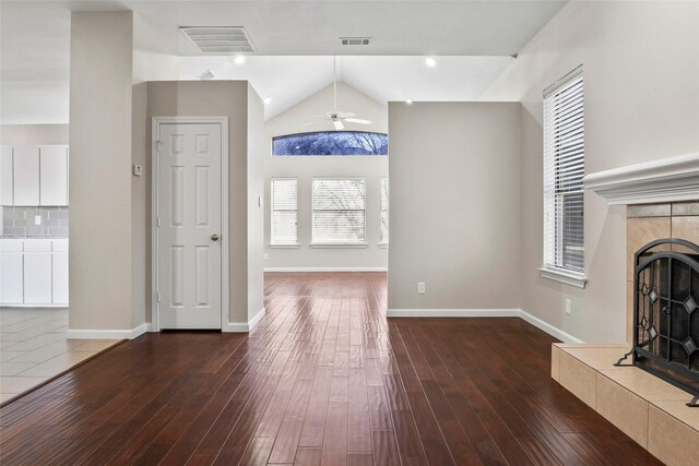 unfurnished living room featuring a fireplace, dark hardwood / wood-style floors, ceiling fan, and vaulted ceiling