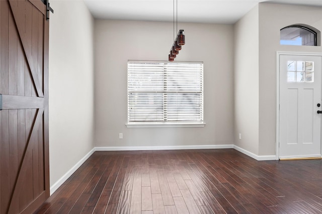 entrance foyer featuring a barn door, dark wood-style floors, and baseboards