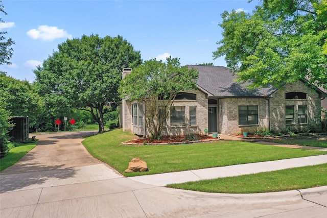view of front facade with brick siding, a front lawn, driveway, and a chimney