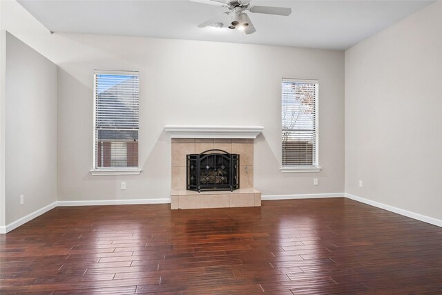 unfurnished living room featuring a wealth of natural light, a tiled fireplace, and wood finished floors
