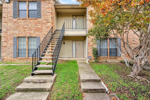 property entrance featuring a balcony and a yard