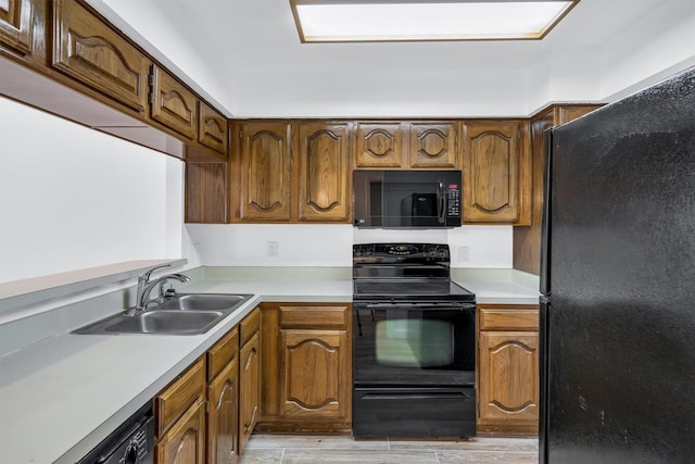 kitchen featuring sink, light hardwood / wood-style flooring, and black appliances