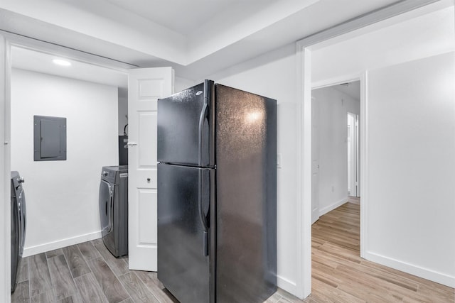 kitchen with black refrigerator, independent washer and dryer, electric panel, and light wood-type flooring