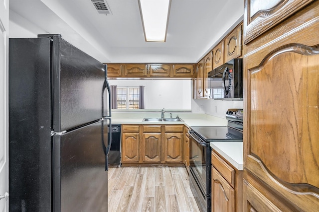 kitchen with sink, a wealth of natural light, black appliances, and light hardwood / wood-style floors