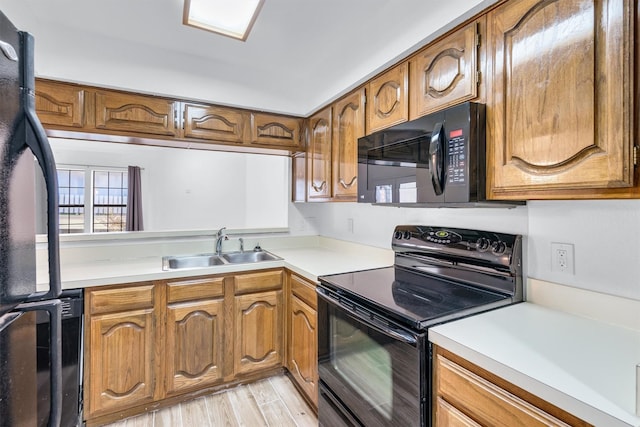 kitchen featuring sink, light hardwood / wood-style flooring, and black appliances