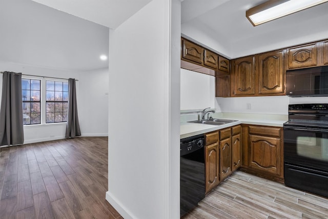 kitchen with lofted ceiling, sink, light wood-type flooring, and black appliances