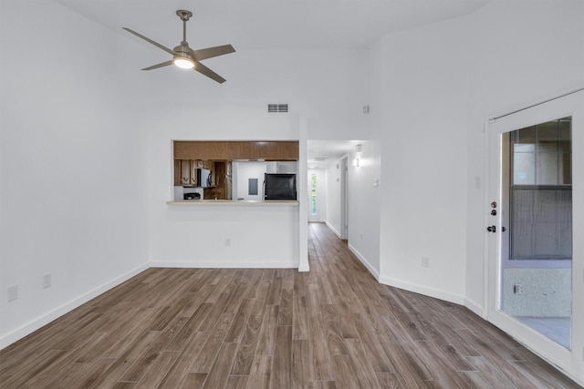 unfurnished living room with a high ceiling, hardwood / wood-style floors, and ceiling fan