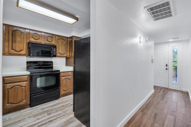 kitchen with black appliances and light hardwood / wood-style floors