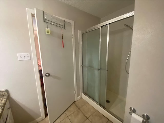 bathroom featuring a shower with door, vanity, tile patterned floors, and a textured ceiling