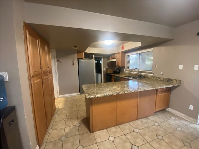 kitchen featuring electric stove, stainless steel fridge, kitchen peninsula, and sink