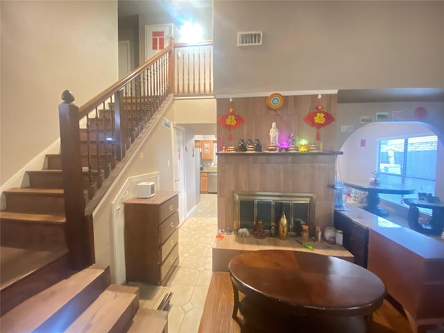 staircase with a tiled fireplace and a towering ceiling