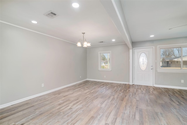 foyer featuring an inviting chandelier, ornamental molding, and light hardwood / wood-style flooring