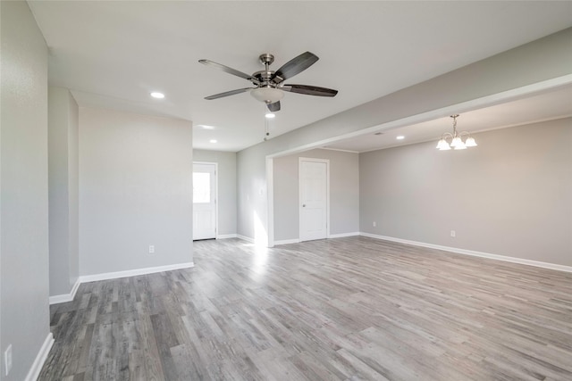 empty room featuring ceiling fan with notable chandelier and light hardwood / wood-style floors