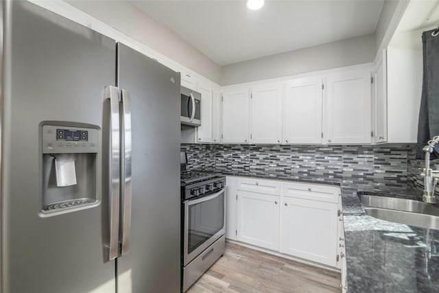 kitchen featuring sink, white cabinetry, light wood-type flooring, stainless steel appliances, and decorative backsplash