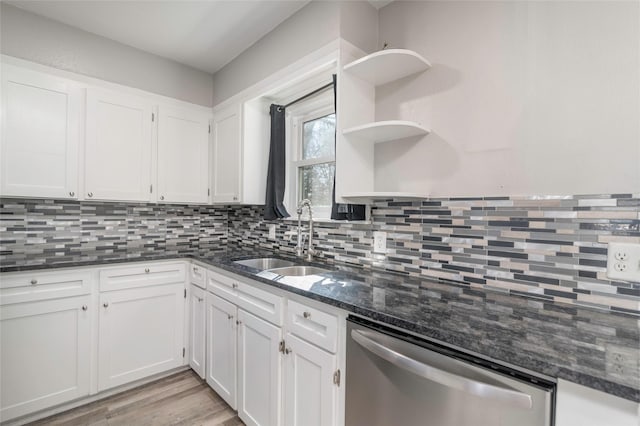 kitchen with stainless steel dishwasher, dark stone countertops, sink, and white cabinets