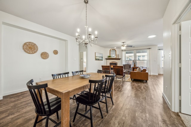 dining area featuring dark hardwood / wood-style floors, a fireplace, and ceiling fan with notable chandelier